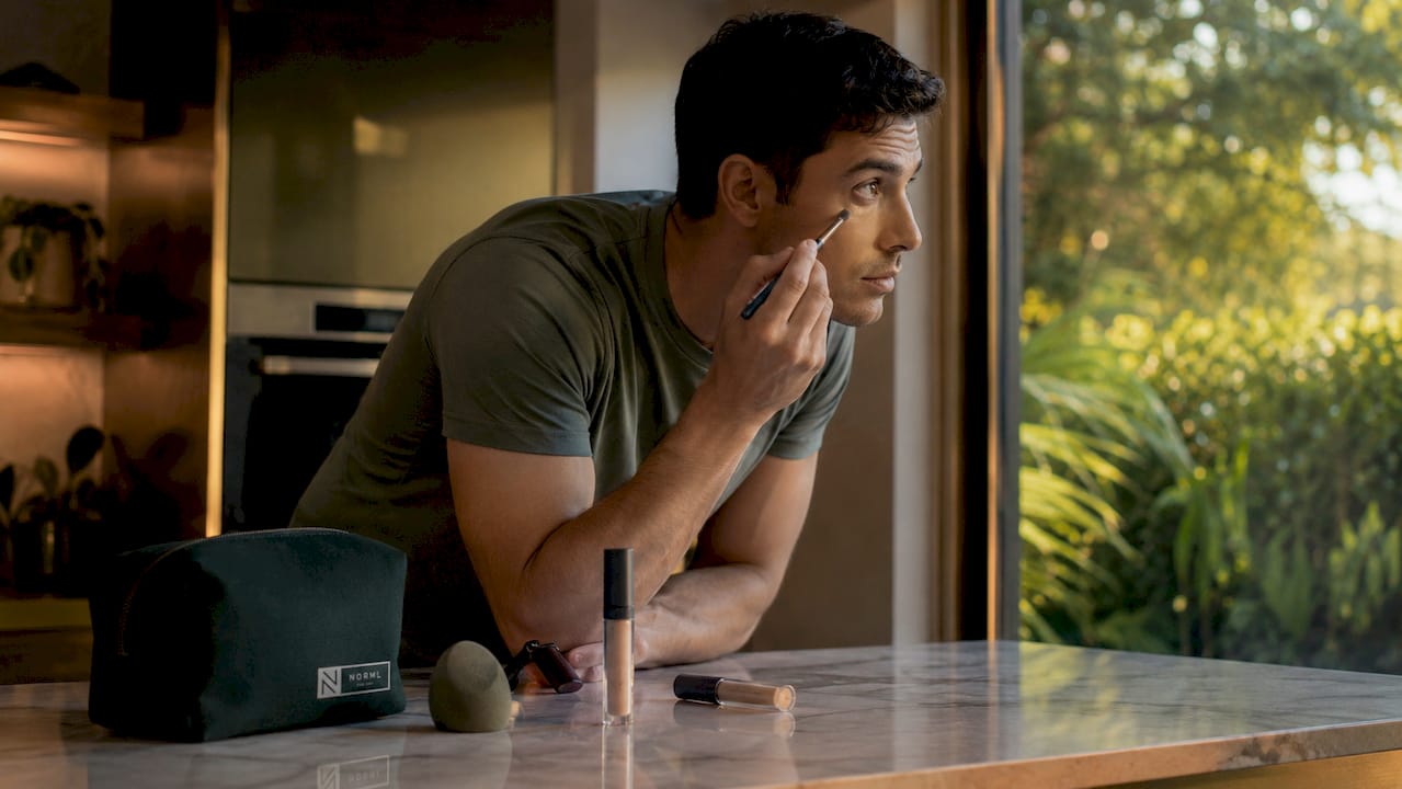 Man applying concealer in bathroom mirror