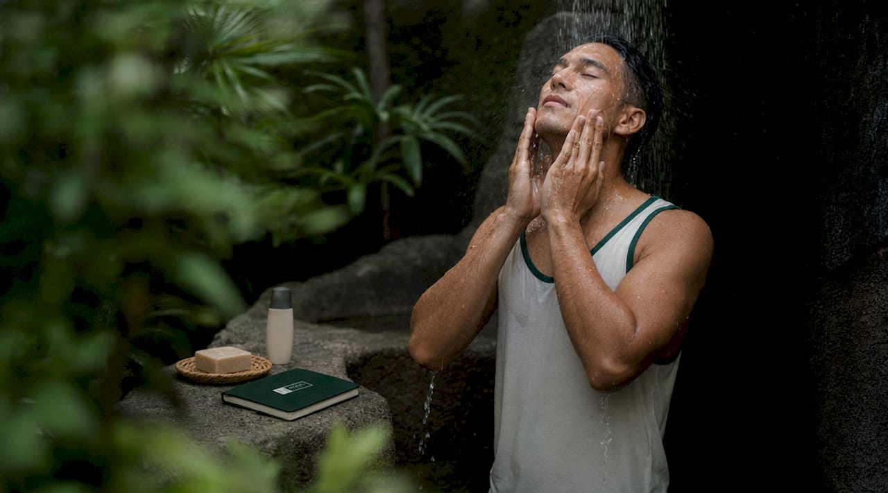 Man washing face in bathroom mirror morning