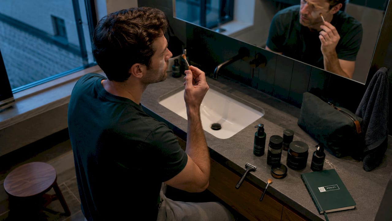 Man applying green concealer to face redness