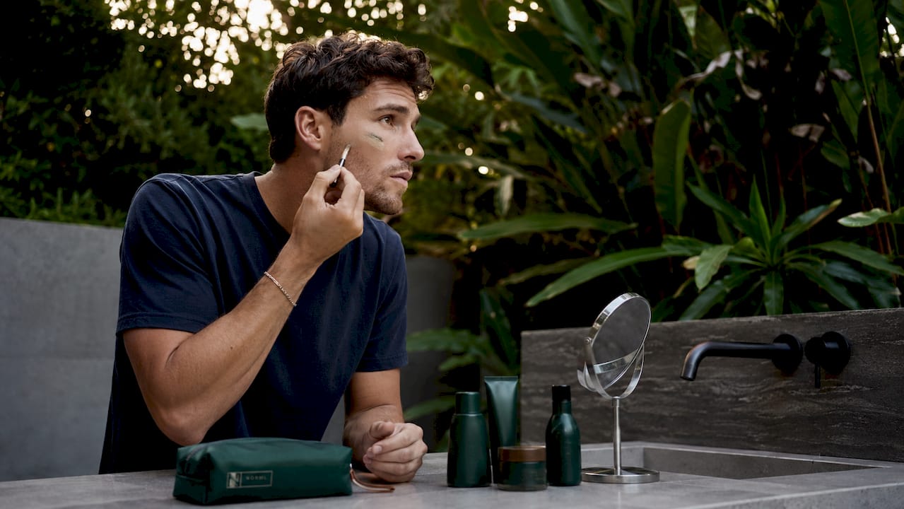 Man applying blemish coverage in bathroom