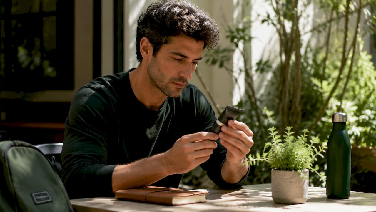 Man considering makeup product at desk
