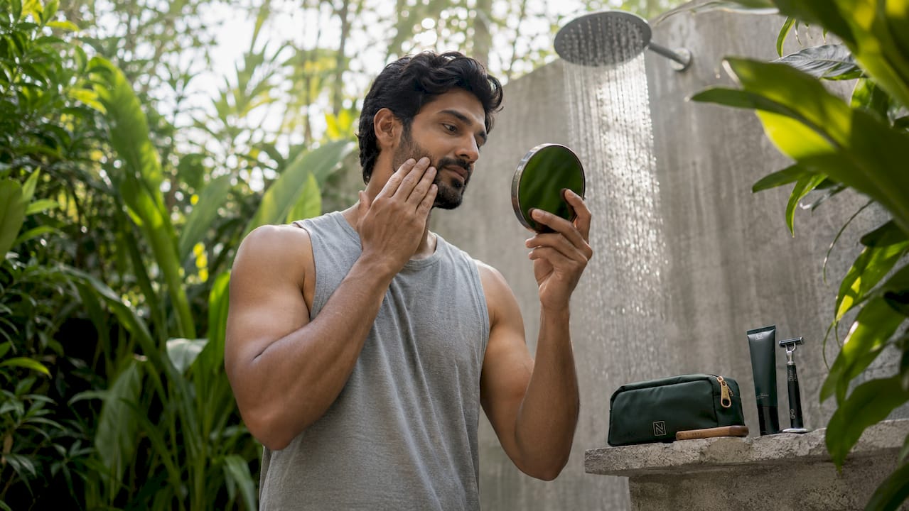 Man applying moisturizer in bathroom mirror